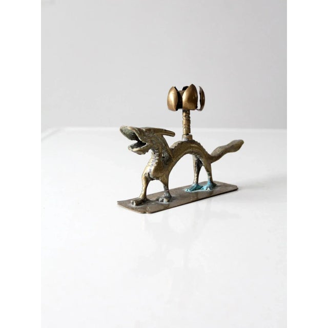 This vintage Chinese brass candlestick holder is crafted in the form of a dragon intertwined with lotus flowers, a...