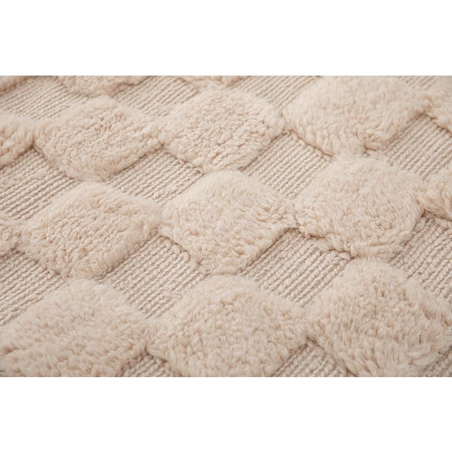 Monochromatic hand-knotted wool rug in a soft Natural Wool hue featuring a raised checkerboard pattern. The textured...