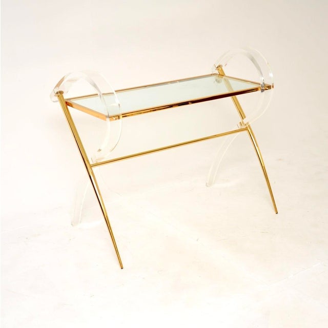A stunning vintage Italian acrylic glass and gold finish console table, dating from the 1970’s. It has a very decorative...