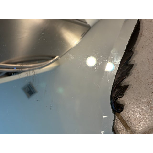 Antiqued Shield Wall Mirror With Carved Scroll Accents An antiqued wall mirror with a shaped shield silhouette and carved...