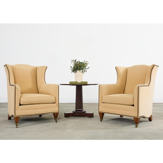 An exceptional pair of bespoke wingback club armchairs from Henredon's Upholstery Collection. The chairs feature towering...