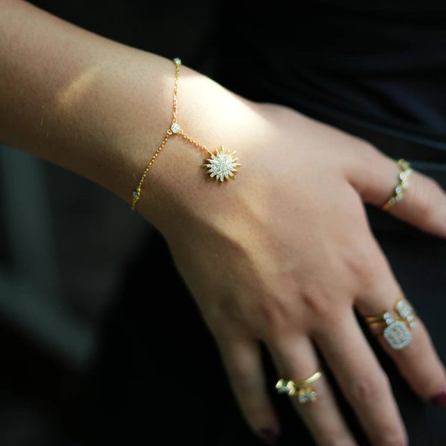 Shine with elegance and style wearing the Diamond & Gold Sun Fashion Style Hand Bracelet. This exquisite piece features...