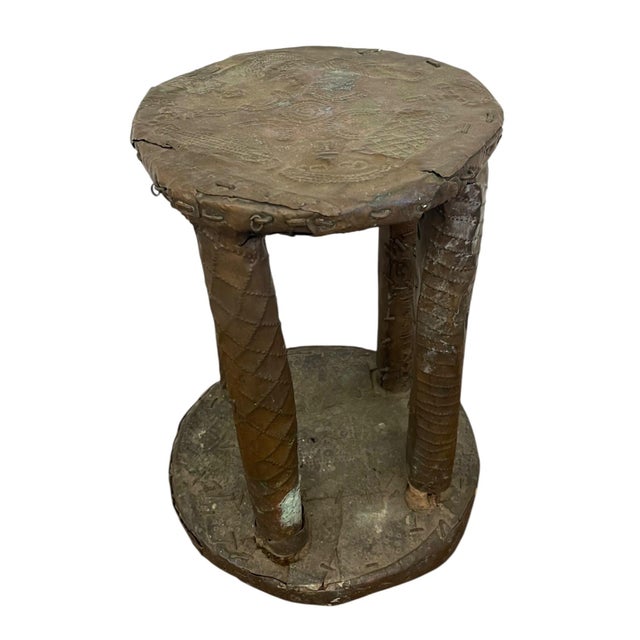 This decorative stool or low pedestal features a cylindrical, four-leg form with a round top and base, all clad in thin...