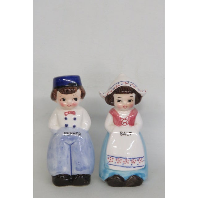 This lovely Pair of Salt and Pepper Shakers is made of ceramic. These two shakers present the design of a Dutch Girl with...
