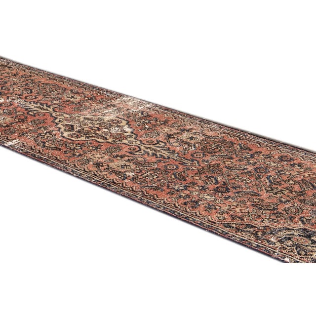 Beautiful vintage Persian Distressed hand-knotted wool runner with a red field. This rug has a beige and brown accent in...