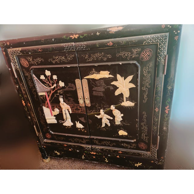 This is a mid-20th century Chinese export lacquer cabinet with carved soapstone or bone appliqué figures and scenery. The...