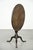 This elegant and practical round antique English tilt-top table from the 18th century features a luxurious, warm color and...