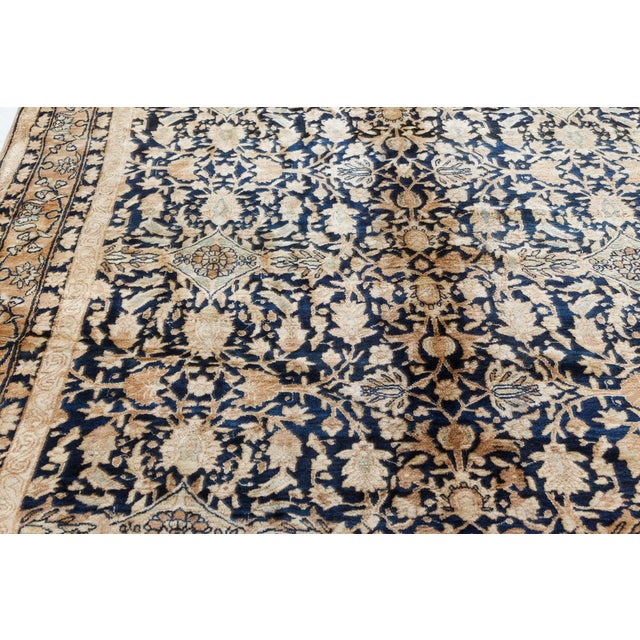 An early 20th century Persian Kirman (Kerman) antique rug, the black field with a flowering vine and palmette trellis...