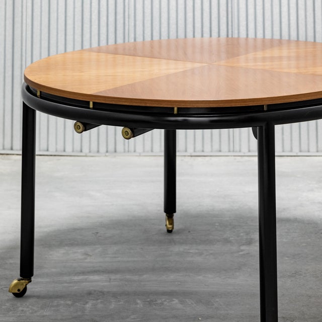 Elliptical dining table by Michael Taylor for Baker (unmarked), book matched wood grain top, with black lacquered base and...