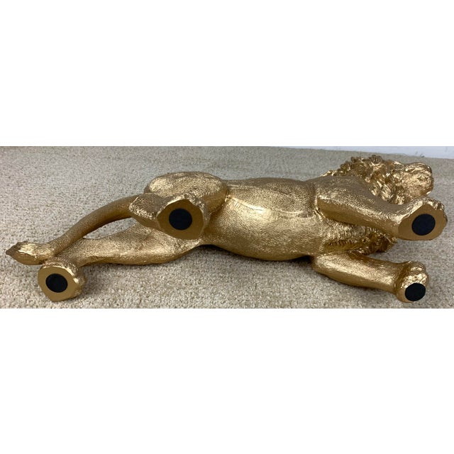 This decorative gold resin figurine walking lion sculpture featuring a finely textured mane and a gleaming metallic finish.