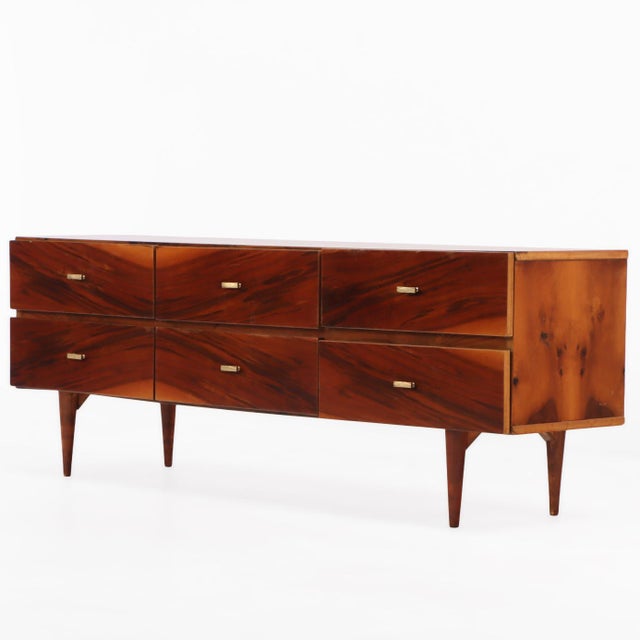 A handsome mid-century walnut dresser distinguished by its richly figured and bookmatched veneered drawer fronts that...