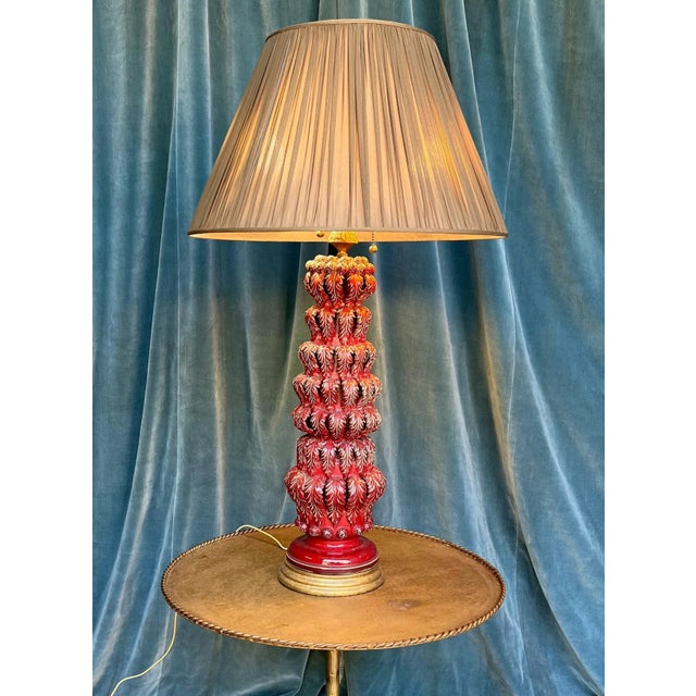 This elegant Spanish deep red glazed ceramic table lamp from the 1950s features stylized draped leaf decorations. Mounted...