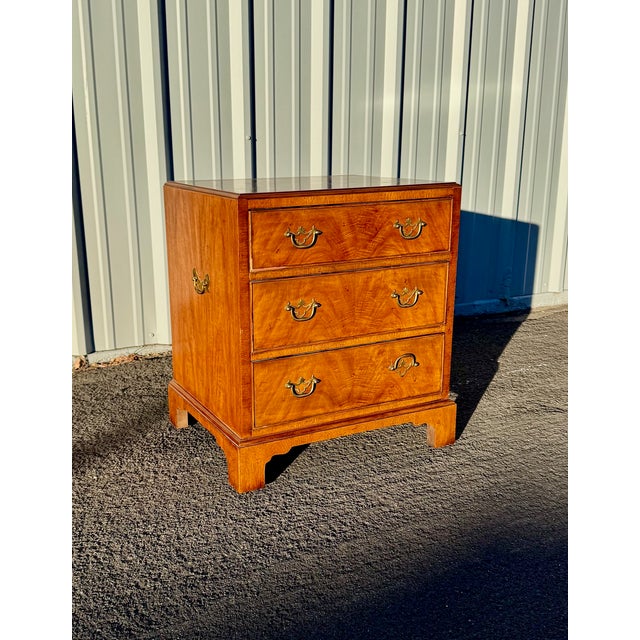A three drawer bedside chest in the Chippendale style made by Henredon circa 1970's. Made from walnut with brass hardware,...