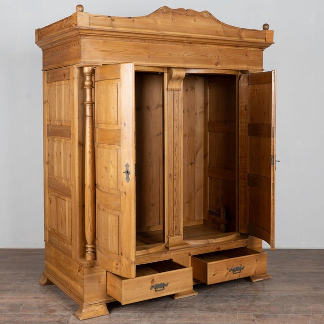 19th century Danish country armoire crafted in pine. The cabinet features two bowfront doors flanked by turned columns....