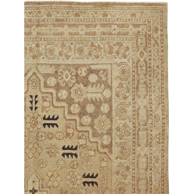 This mid-20th-century East Turkestan Khotan rug presents a restrained geometric composition in warm beige, sand, ivory,...