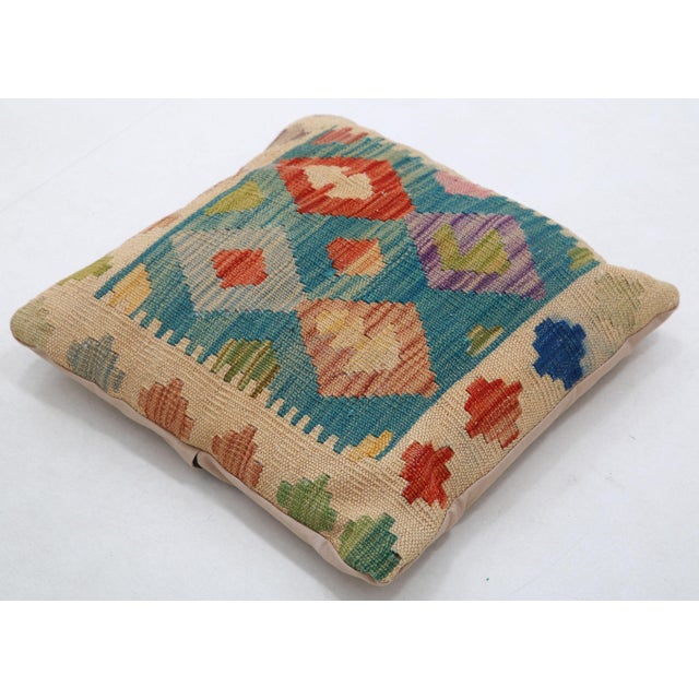 A one-of-a-kind handwoven Afghan wool kilim accent pillow featuring vibrant zigzag diamonds in green, red, and blue. Cut...