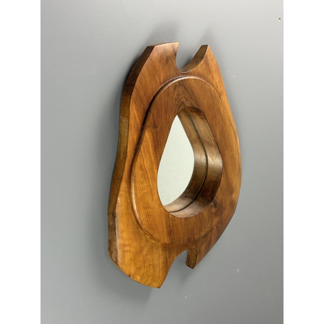Sculptural wall mirror from France, 1960s, with a freeform carved wood frame. The outline is asymmetrical, with two curved...