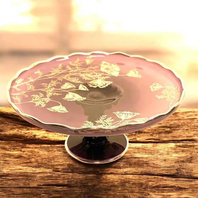 This early 20th-century amethyst glass cake plate features a scalloped rim and a solid pedestal base, finished with a...