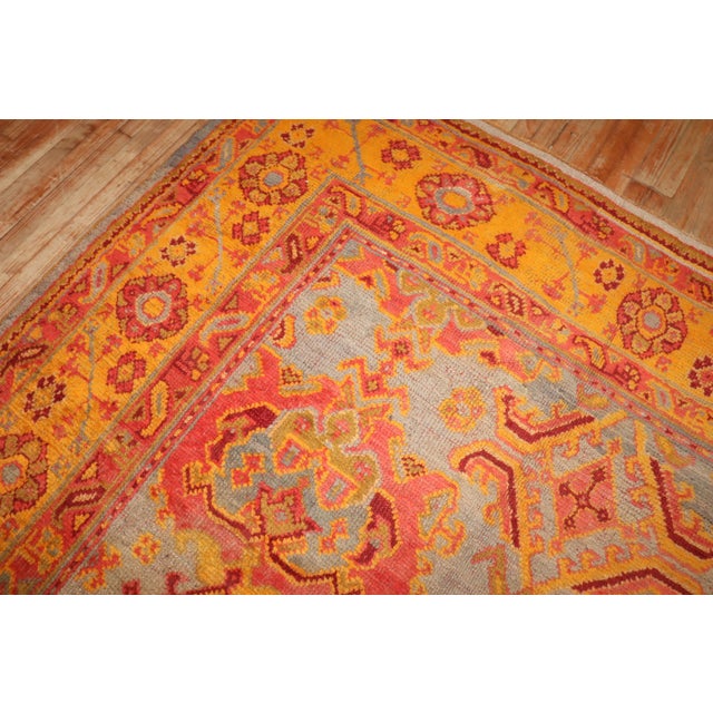 An antique Turkish Oushak rug featuring a silver shaded field, mustard border, with other vibrant and bright color...