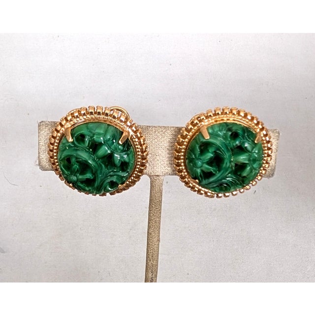 1965 round goldtone carved faux-jade butterfly clip back earrings. Marked "NAPIER PAT. PEND." on the clips and on the...