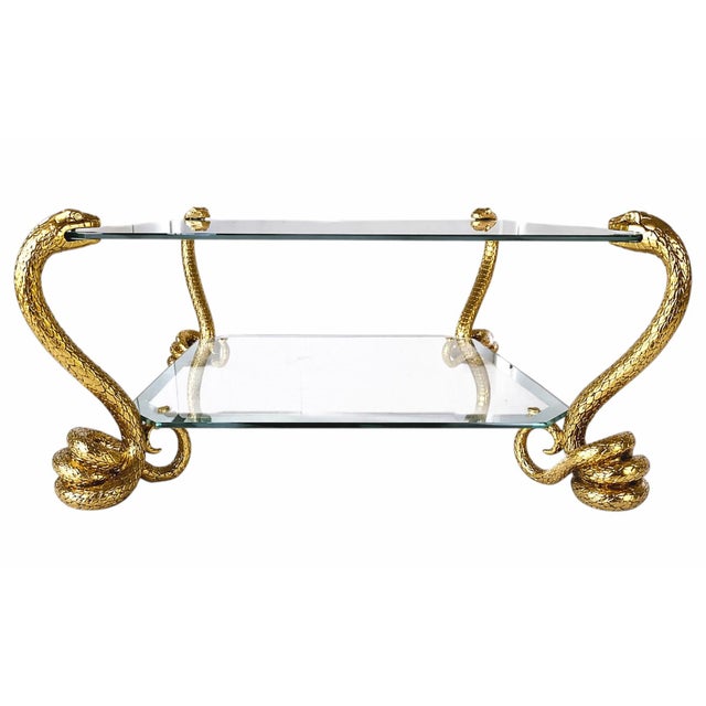 Four coiled snake forms rise through the design, holding the upper glass within their open mouths while the lower tier...