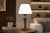 Table lamp dating to the 1950s, with a tall tapered metal column wrapped in navy blue leather. Brass accents at the top...