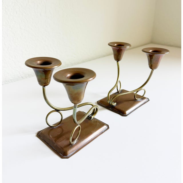 A pair of 1950's mixed metal brass and copper candlesticks in the style of Mexican maker Los Castillo. Features a copper...