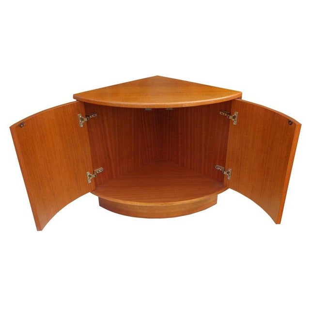 Danish teak corner cabinet side table Space saving mid-century corner cabinet in teak on a plith base. Two doors open to...