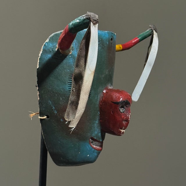 Hand carved and polychromed, the mask features a red skull motif integrated into the snout, with incised and painted eyes....