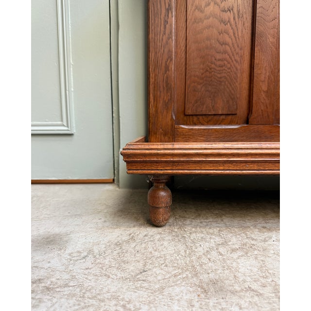 Elegant solid oak entryway coat rack dating from the early 20th century. Tall and narrow, it combines a coat rack, mirror,...