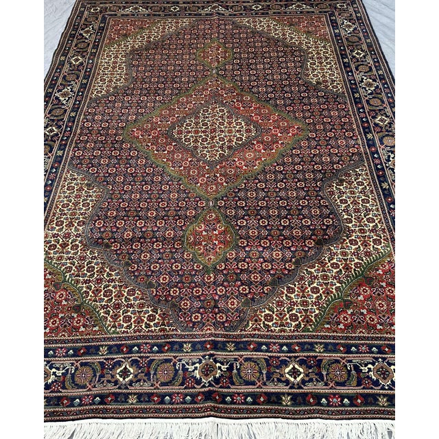 The central medallion of this hand-knotted rug commands the room before anything else does. A large diamond form in ivory...