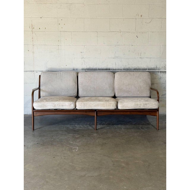 This three-seater sofa features a sculpted frame and an elegant open spindle back. The curved armrests transition...