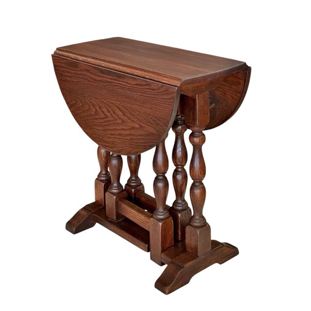 A handsome William and Mary–style drop-leaf side table crafted in oak and having a gate-leg base supporting an oval top...