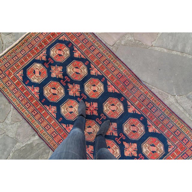 This vintage Khotan rug highlights 12 geometric medallions organized in 2 rows, with small goat figures inside the...