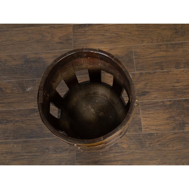A rustic English turn of the century oak barrel from the early 20th century with six brass braces and open accents, made...
