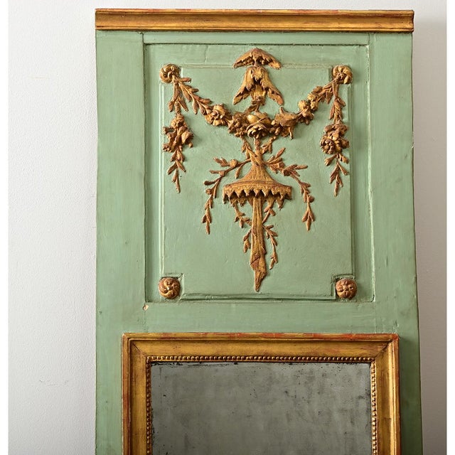 An exceptional trumeau mirror from 18th century, France, carved and parcel gilt on boiserie paneling in a weathered aqua....
