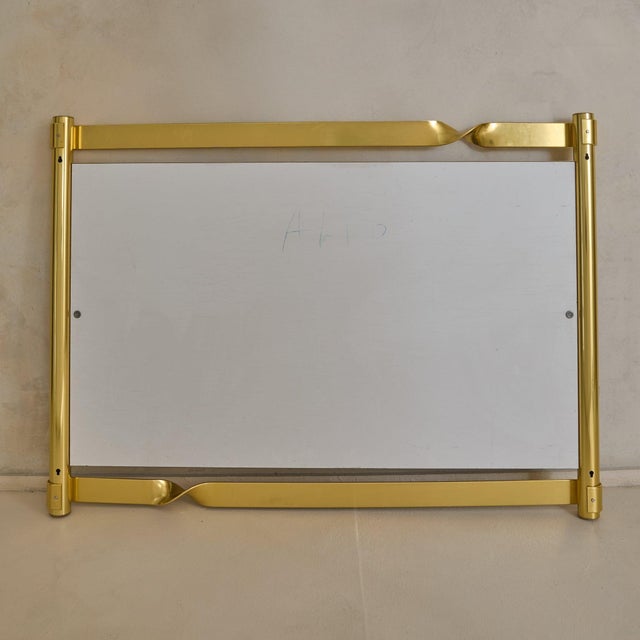 A sculptural Italian wall mirror by Luciano Frigerio, 1970s. The polished brass frame is shaped with twisted ribbon-like...