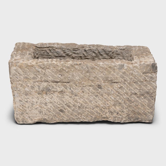 Once a common sight in courtyards throughout rural China, this textured stone vessel was used as a grain or water trough...