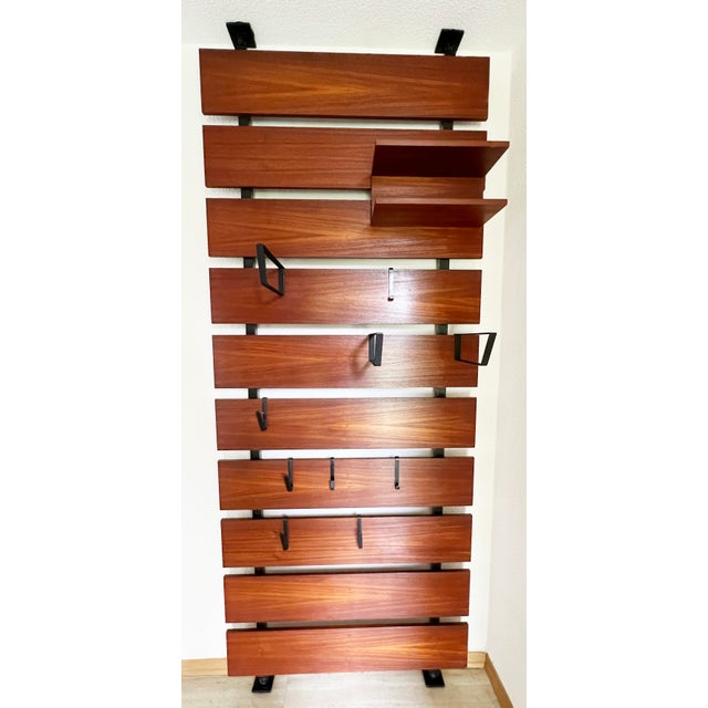 A teak and steel wall coat rack 1960s. Very stable design The wardrobe is tensioned between the floor and ceiling using...
