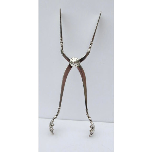 Magnolia pattern tongs with spring action to use with sugar cubes, ice cubes, or serving pieces. The length is 6" long and...