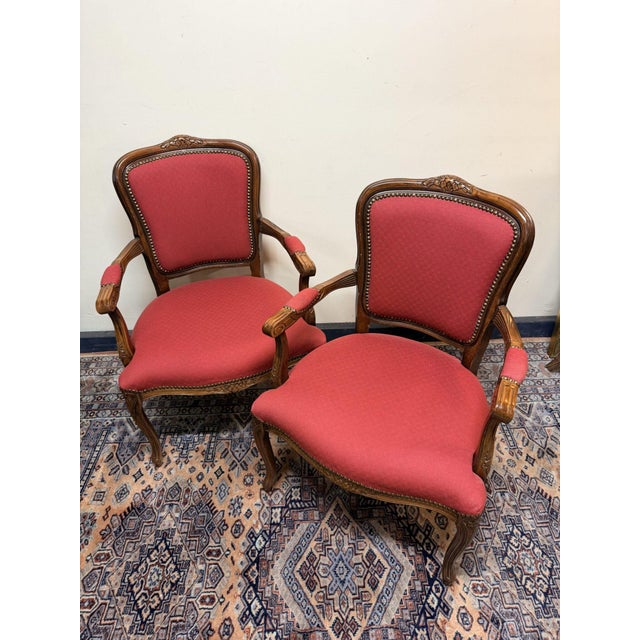 A charming pair of fruitwood armchairs, each featuring a beautifully carved foliate top rail above an upholstered back...
