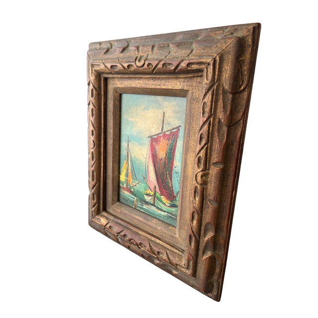 Richly textured oil painting of two sailing vessels at harbor, set in a carved giltwood frame with a warm, aged patina....