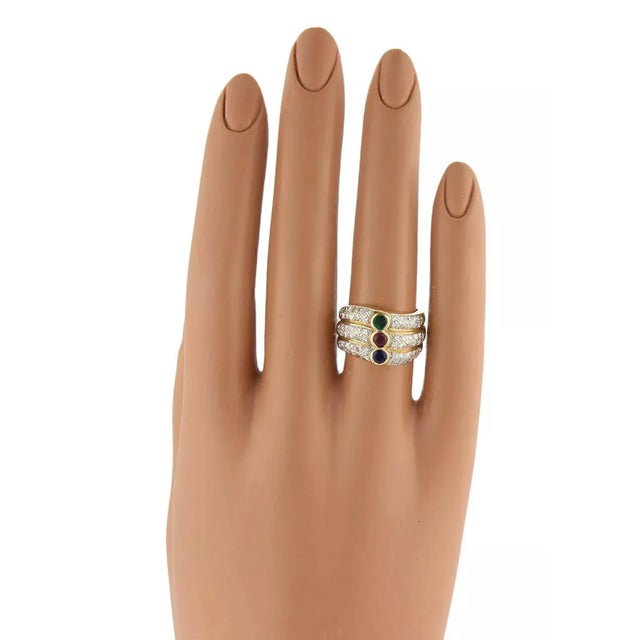 A stunning diamond and gemstone ring in 18k yellow gold with a high polished finish. It has three rows of stacked bands....
