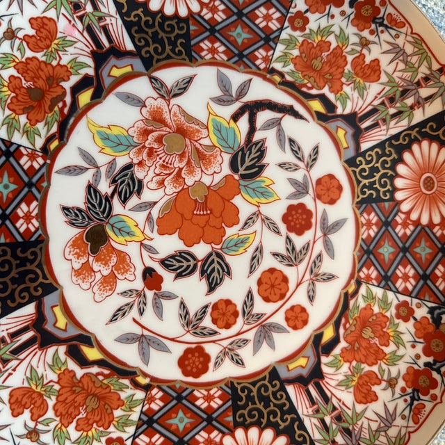 A striking 10 1/4” vintage Japanese Imari plate featuring bold floral panels, a scalloped rim, and the classic Imari...