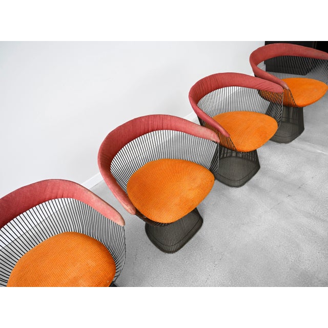 Set of four bronze wire frame upholstered dining chairs in original burnt orange and red fabric. Designer: Warren Platner...