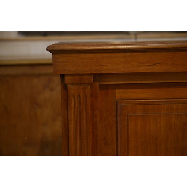 An imposing piece of antique wooden cabinet, featuring straight lines, molded panels, slightly fluted uprights, and a...