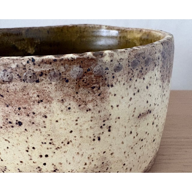 A substantial studio pottery bowl with a softly irregular cylindrical form and a richly contrasting glaze treatment. The...
