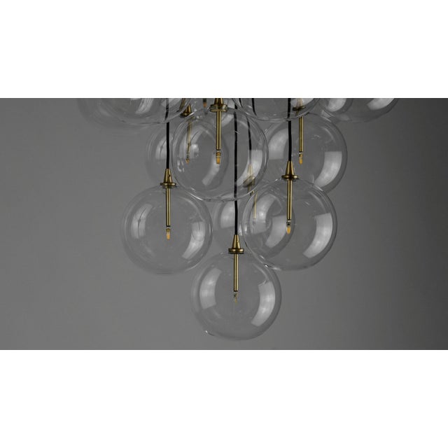 An arrangement of thirteen glass globes suspended from a discus of brass forms a serene ceiling constellation. The...