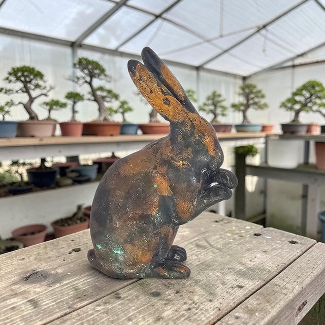 A mid-20th-century Japanese cast-iron rabbit sculpture, naturalistically modelled in a seated posture with elongated...
