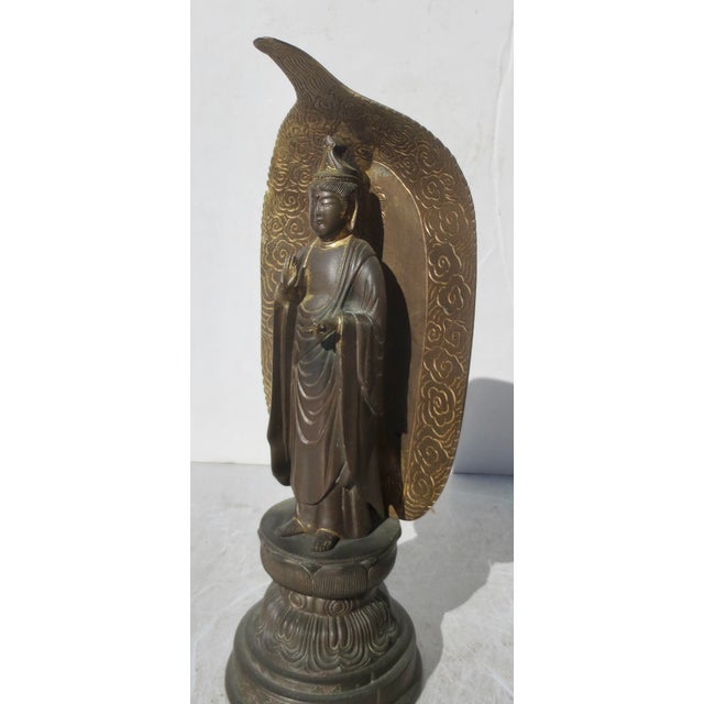 Standing Kannon with a full lotus petal mandorla, standing on a high double lotus throne with a stepped plinth. Backed by...